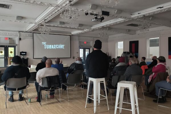 People gathered watching The Sugarcane Film