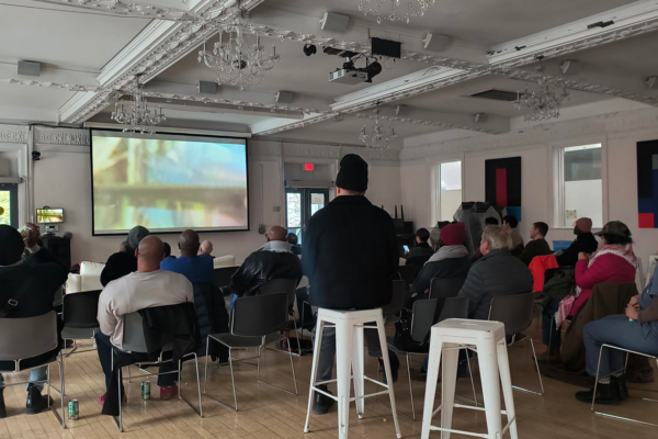 People gathered watching the screening for ReFraming Histories at The 519.